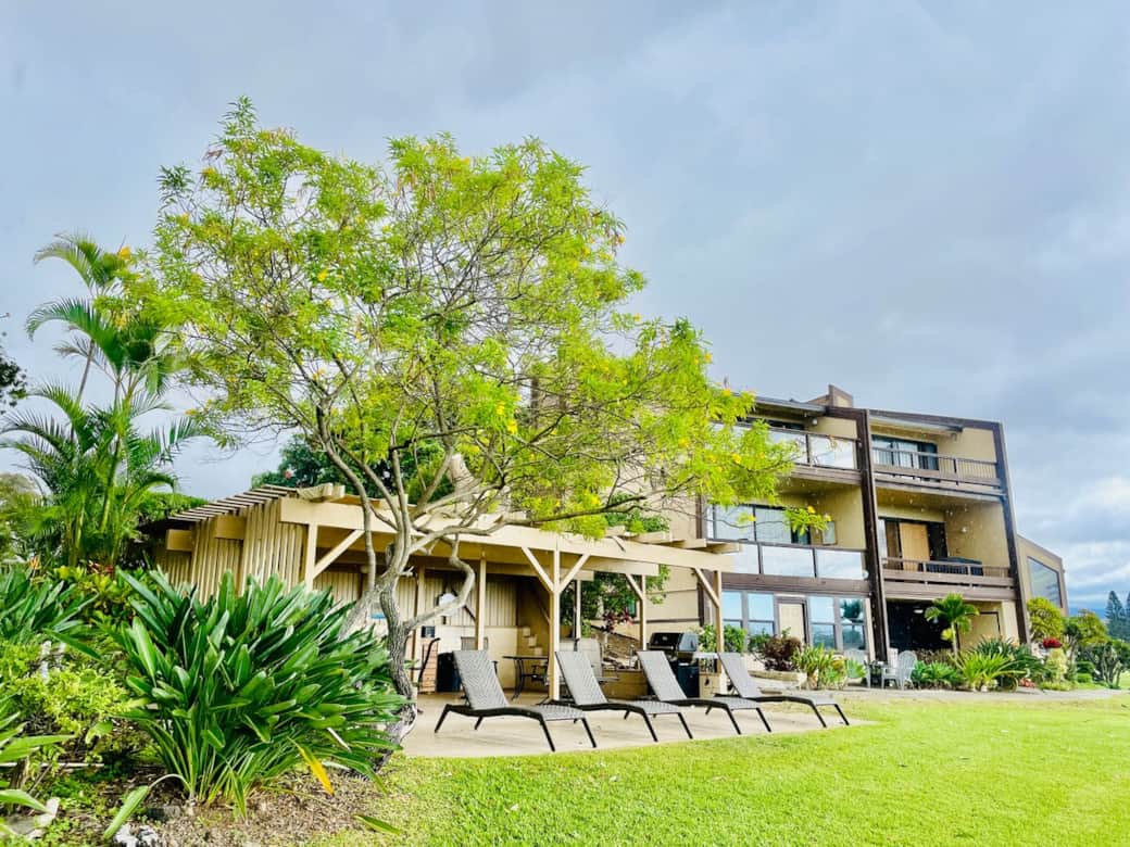 Outdoor BBQ area featuring picnic tables and lounge chairs, perfect for dining and sunbathing under the Hawaiian sun.