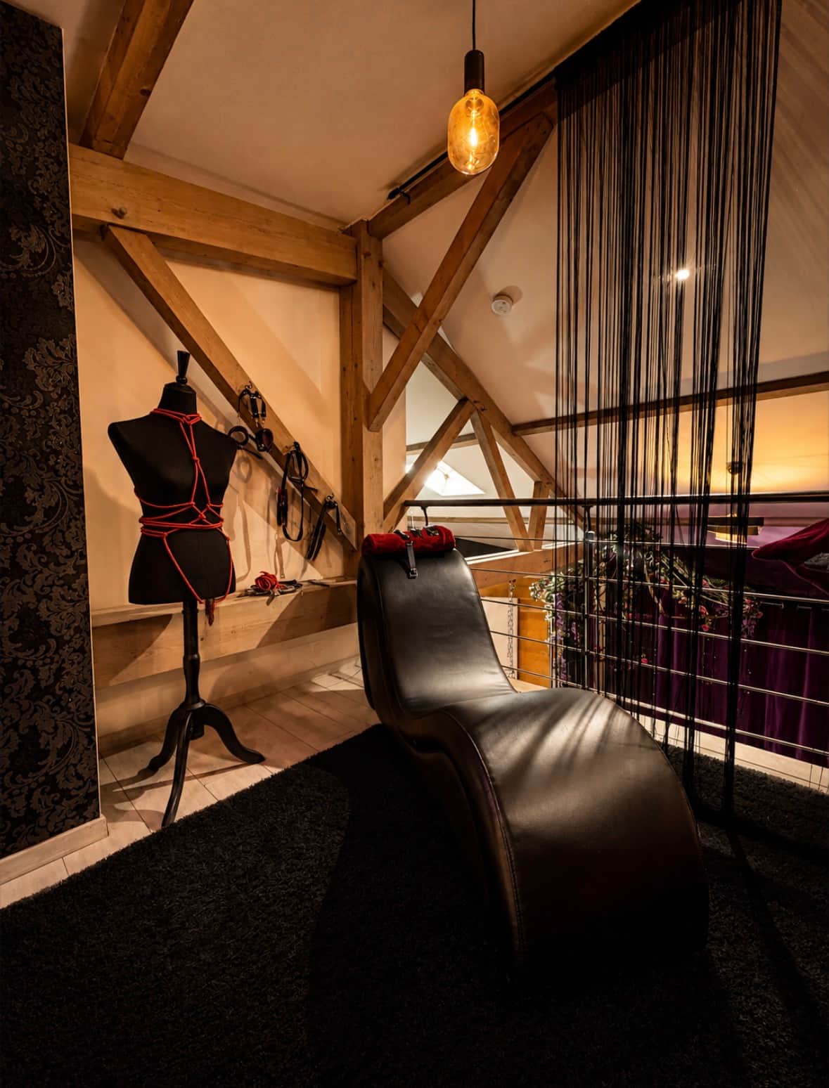 Espace love room en mezzanine avec fauteuil tantra et accessoires érotiques à disposition 