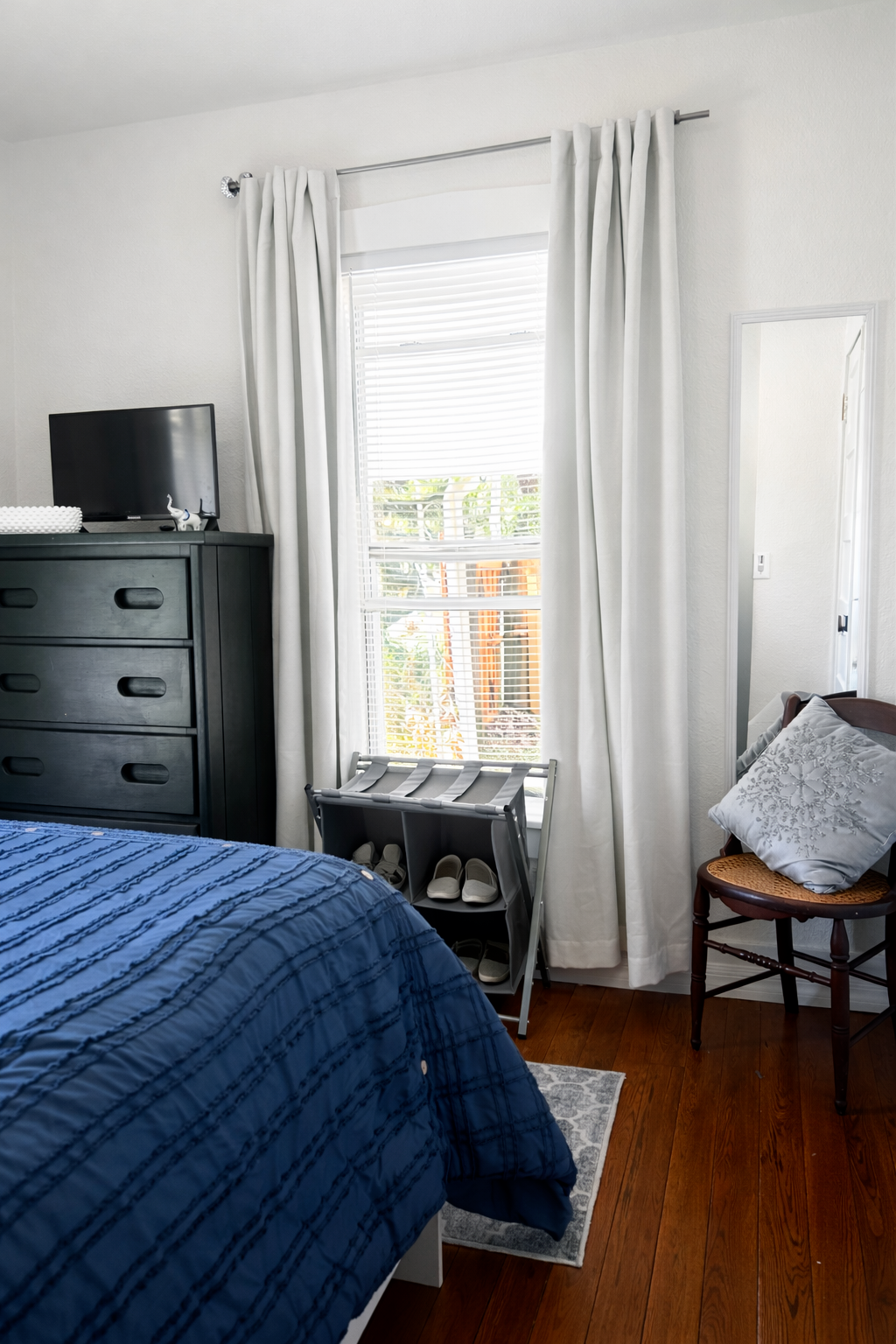Clean, cozy bedroom with rich blue bedding, cheerful artwork, 