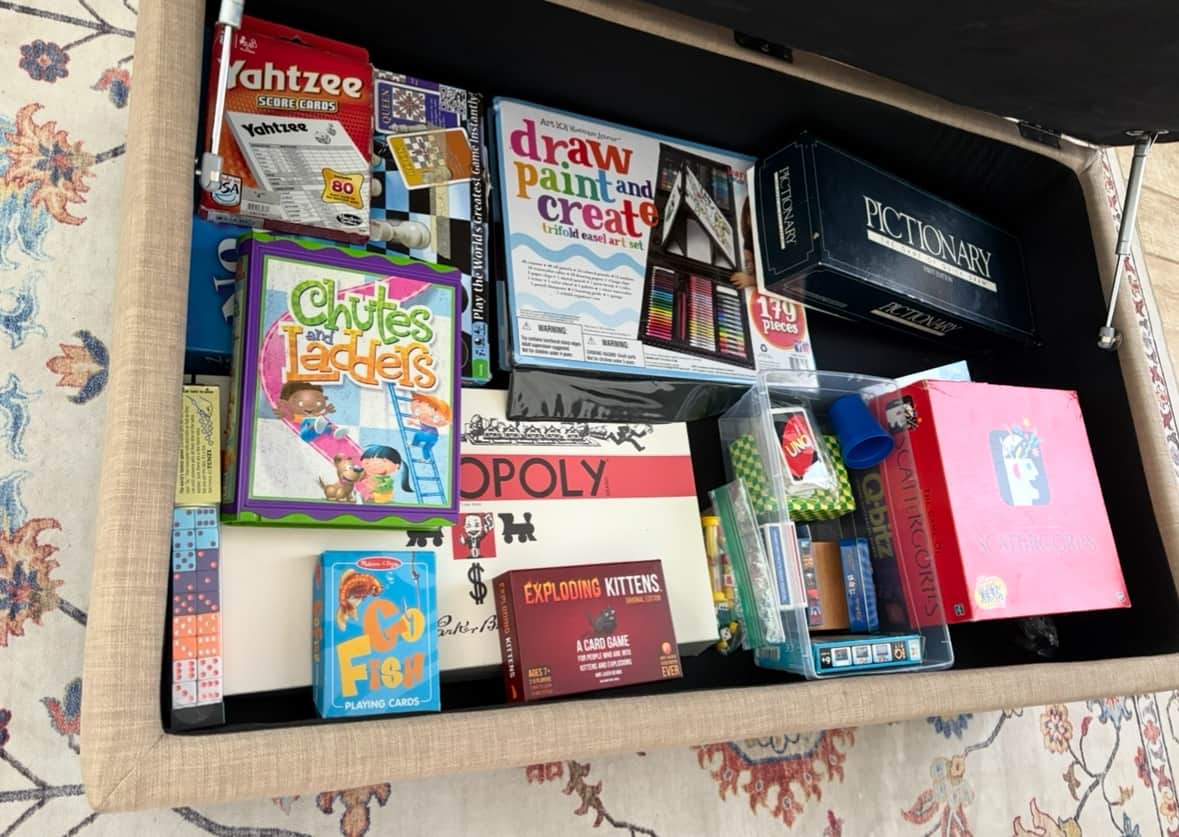 Ottoman with games, puzzles, cards, and drawing supplies.