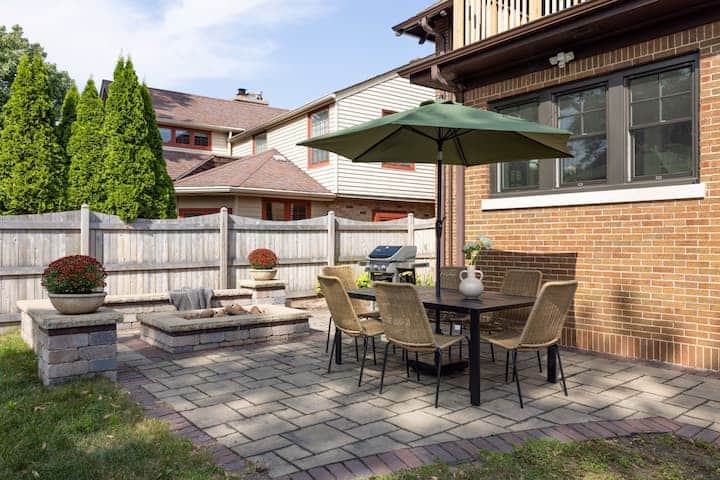 Private backyard patio with outdoor dining table, umbrella, and BBQ grill