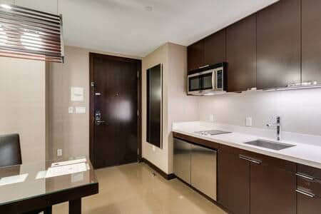 Modern galley kitchenette with mini refrigerator and quartz countertops