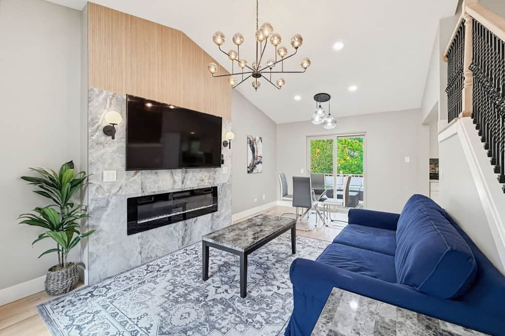 Living Room 1: Sun-drenched main living area with vaulted ceilings and a large flat-screen TV.