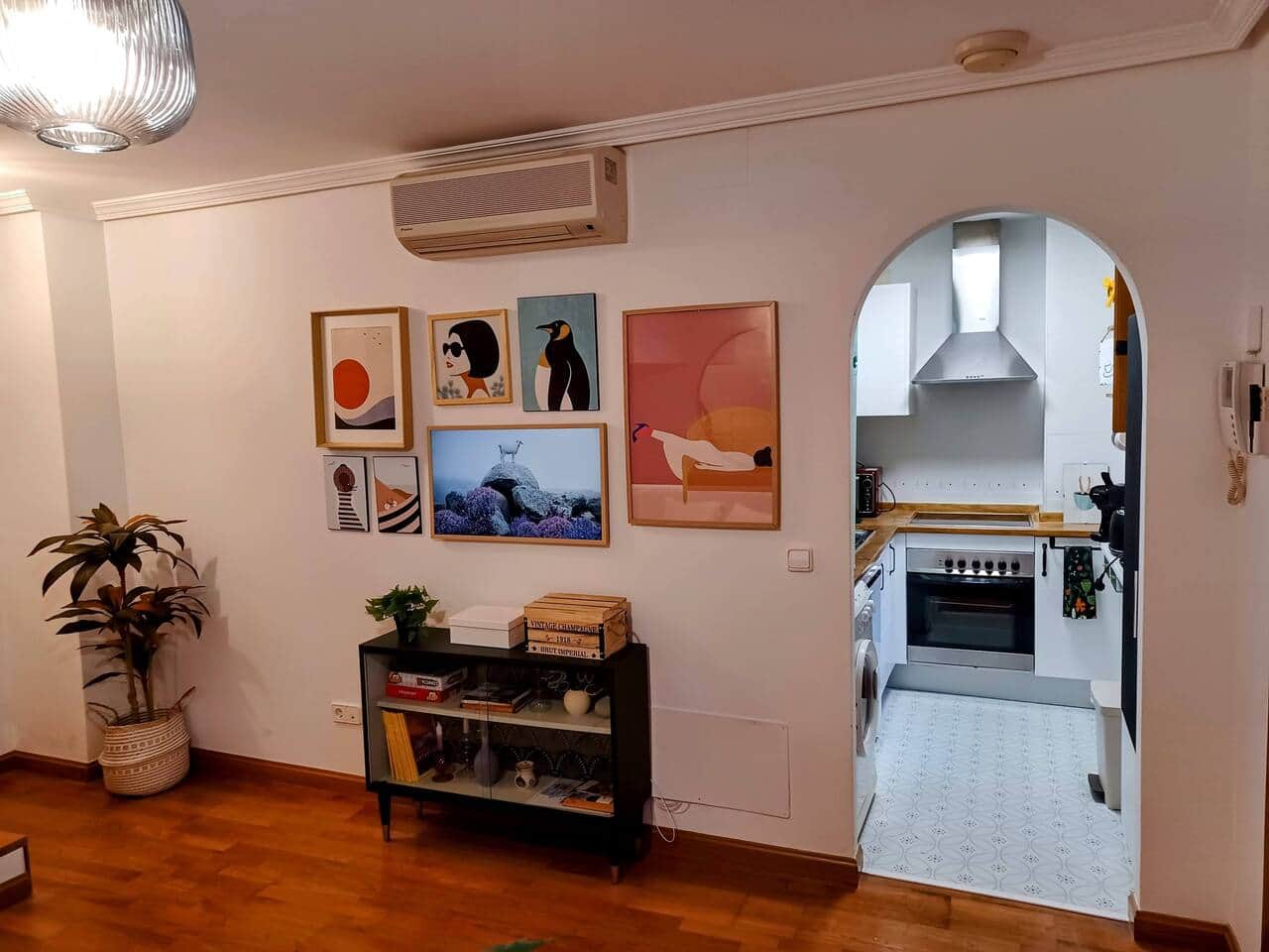 Salón con arco de paso a la cocina y láminas de colores