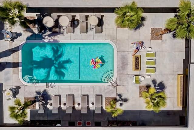 An aerial view of a swimming pool with lounge chairs and palm trees