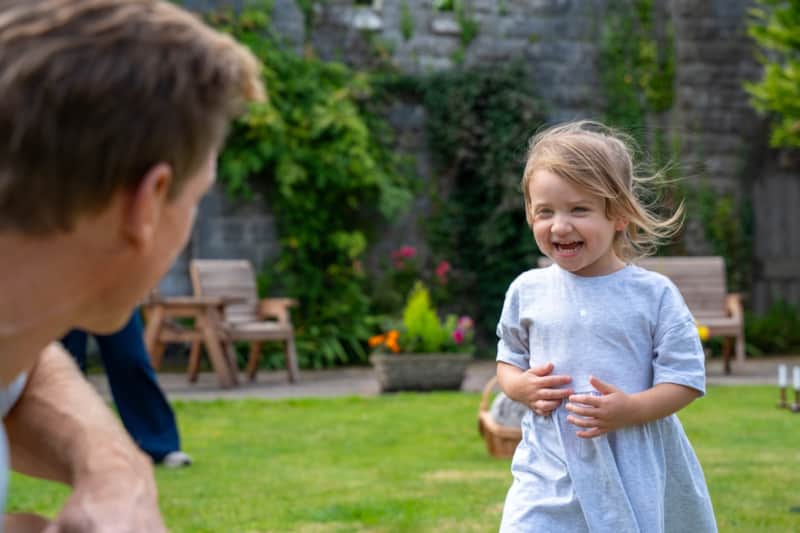 A little girl laughing on the lawn in the walled garden