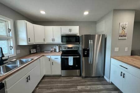 This fully updated kitchen features modern white cabinetry, stainless steel appliances.