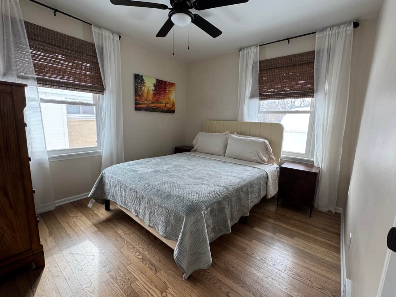 Inviting bedroom with a plush bed, warm hardwood floors, and plenty of natural light. 