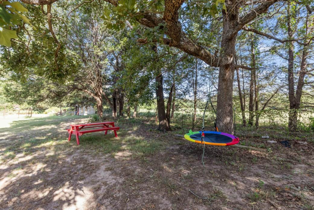 “A playful nook under the trees with a colorful swing and picnic table—perfect for kids to enjoy outdoor fun while parents relax nearby. A cozy corner that combines shade, laughter, and family time.” ✨