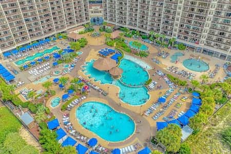 Aerial view of North Beach Resort featuring multiple pools, lazy river, hot tubs & tropical landscap