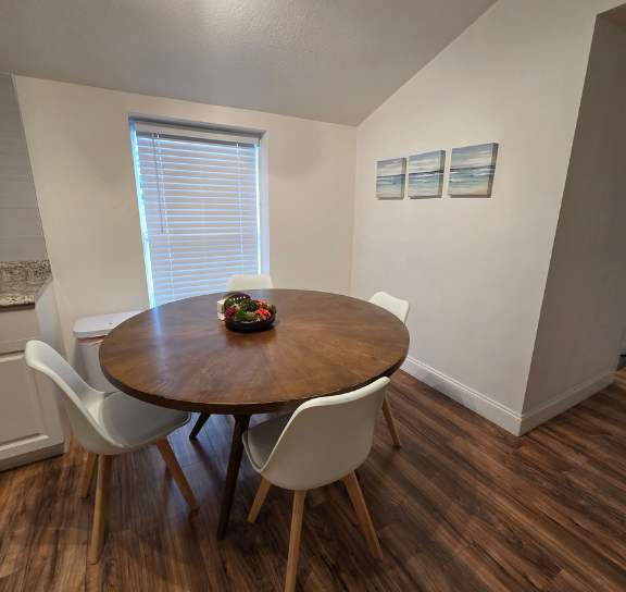 Dining area with a beautiful window, elegant blinds, wall art, and seating for four. Lakeland, FL