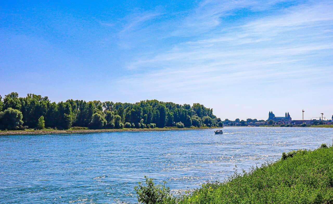 Rhine promenade in Worms with a view across the river and the cathedral silhouette in the distance.