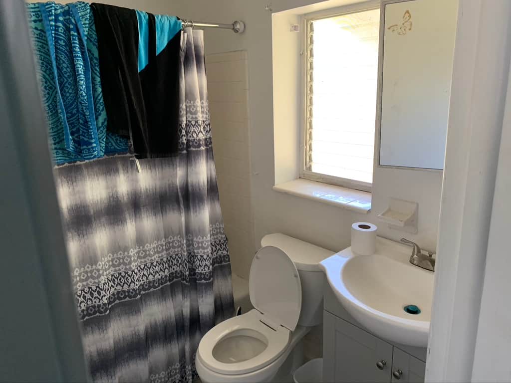 Casa Citron Unit 1 bathroom before renovation with dated fixtures and limited lighting