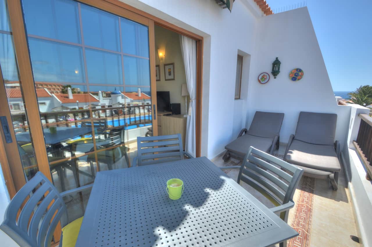 Balcony with sunbeds, table and chairs