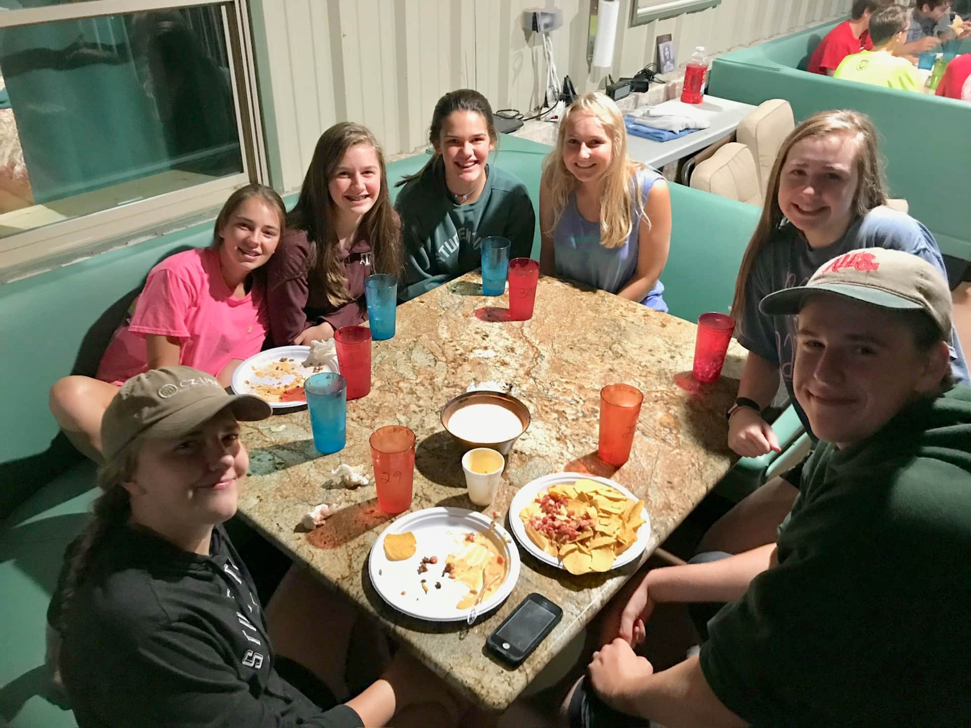 Church youth camp retreat group at restaurant booths on Lake Godstone lodge porch overlooking the lake in Graford TX