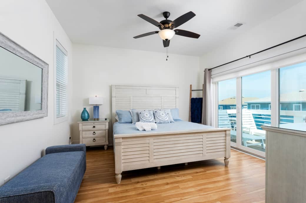 Primary suite with king bed, private bath, and direct access to an ocean-view balcony.