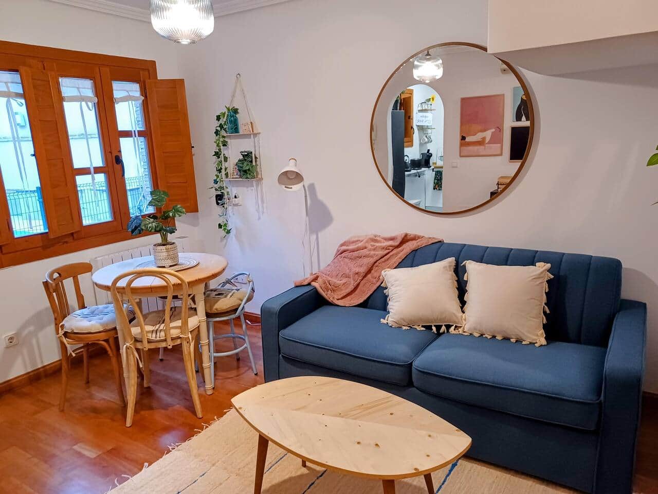 Salón con espejo redondo, sofá y comedor