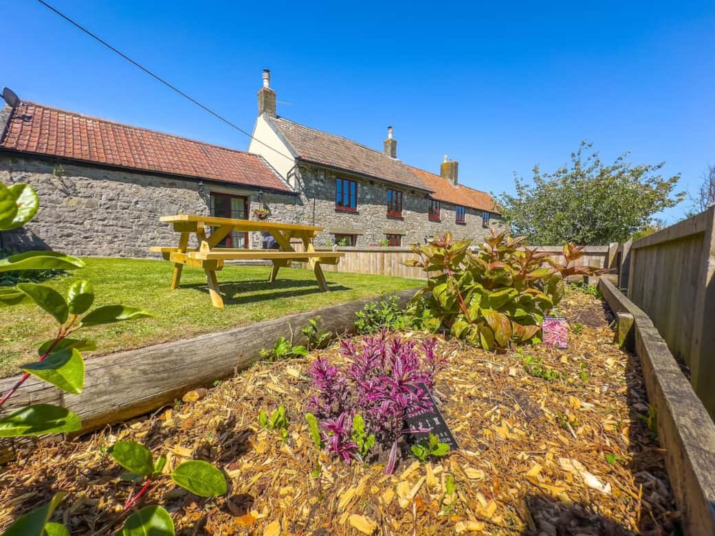 Farm Cottage enclosed garden with large picnic bench and patio doors from the living room