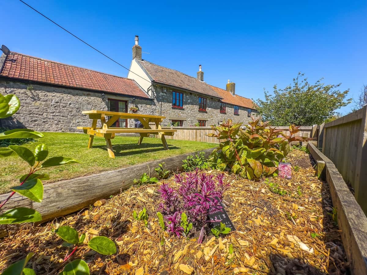 Farm Cottage enclosed garden with large picnic bench and patio doors from the living room