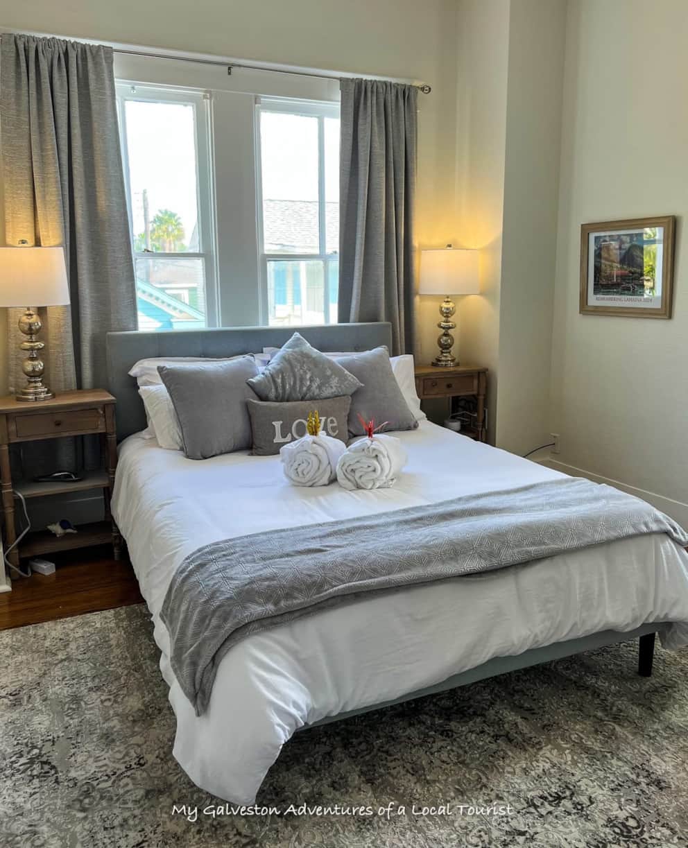 Queen bedroom with balcony access, makeup station, and soft lighting inside White Magnolia Galveston