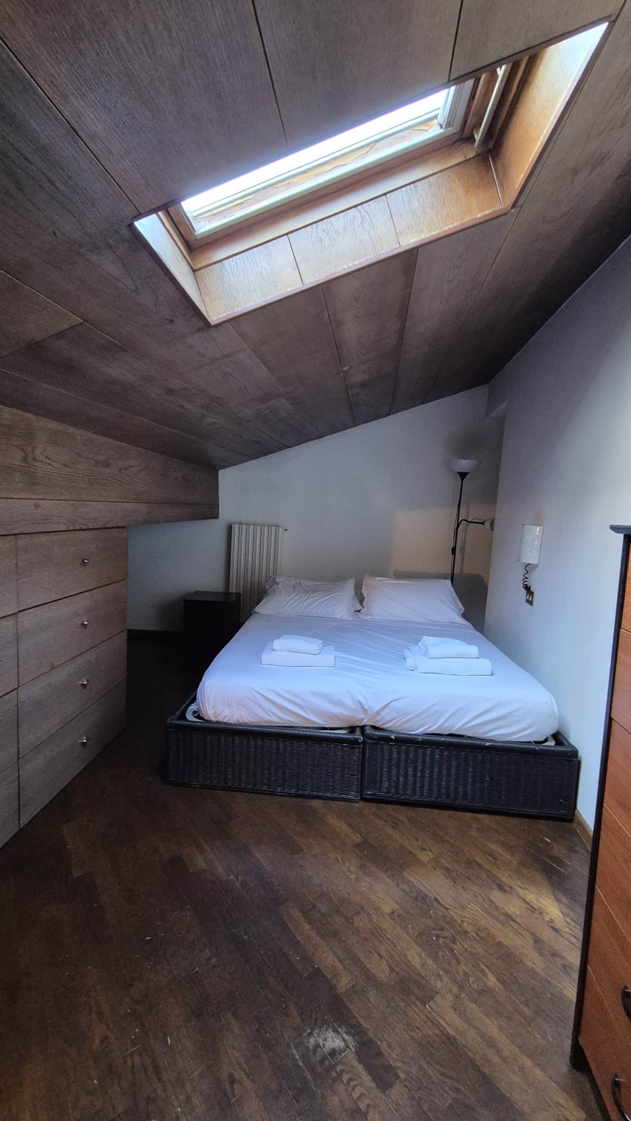 Dormitorio abuhardillado con cama de matrimonio y tragaluz