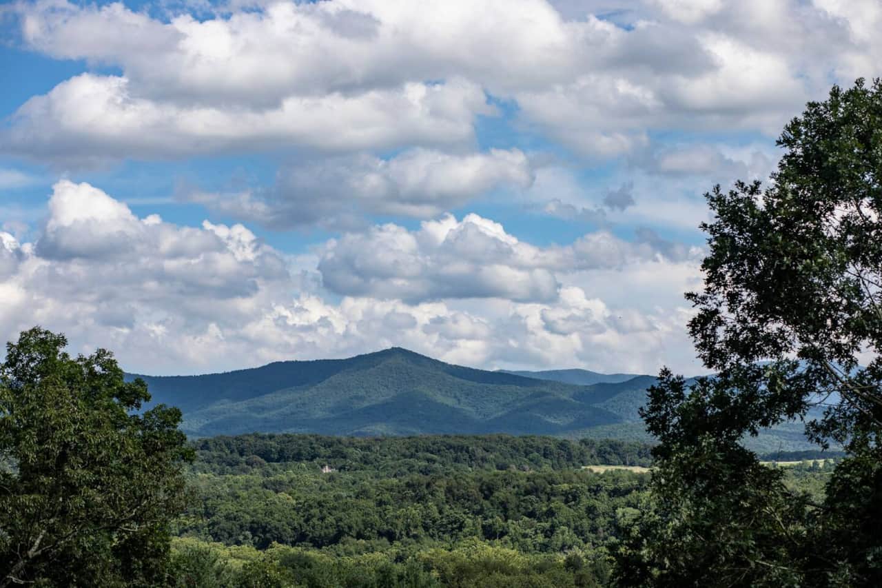 Stunning Blue Ridge Mountain views and lush green forests beneath a beautiful, cloud-filled sky.