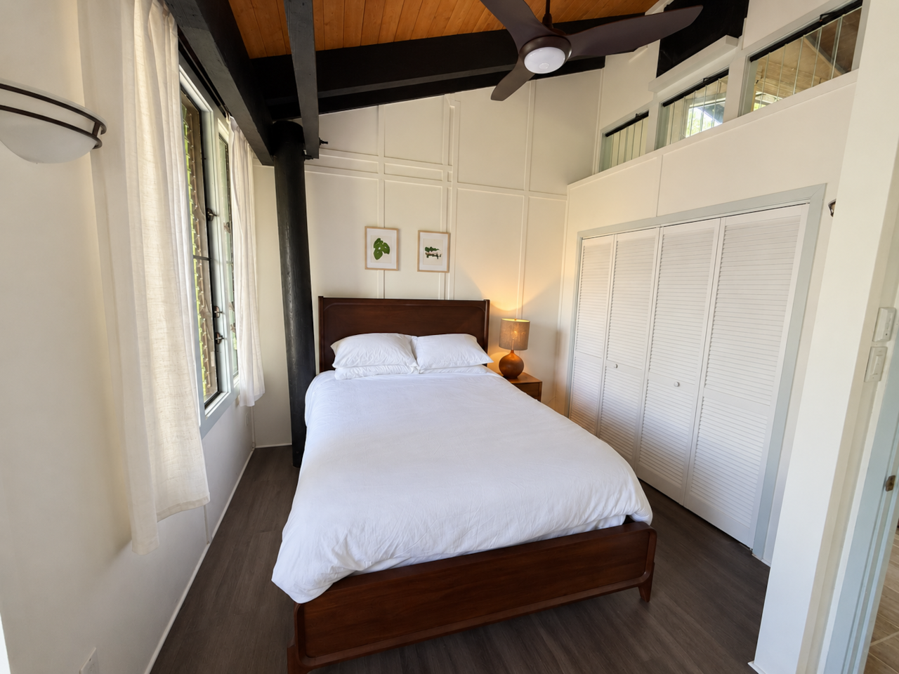 Queen bedroom with large windows and bedside table