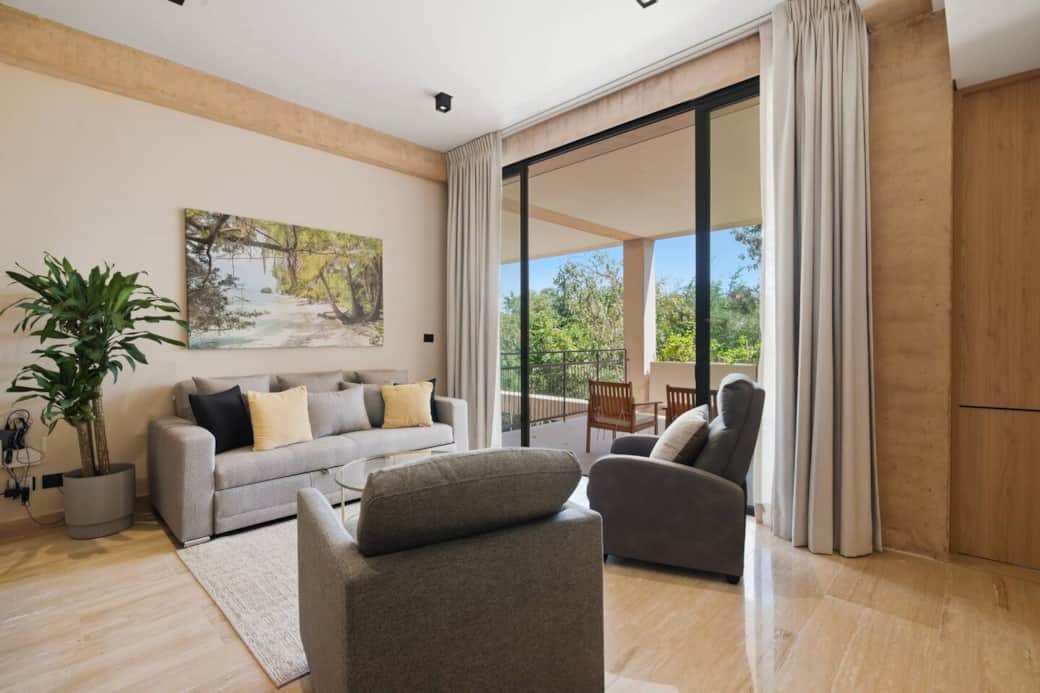 Inviting living room featuring a comfortable sofa bed for extra guests, with direct access to your private terrace overlooking lush greenery, perfect for relaxing and enjoying your stay.
