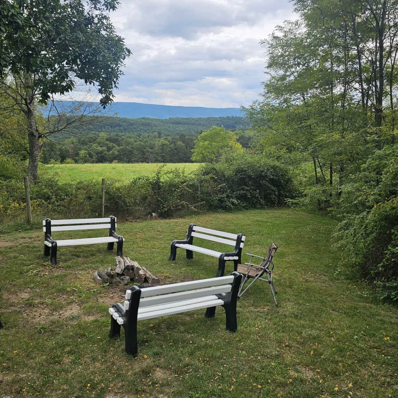 Benches around the fire pit overlooking fields and wooded hills