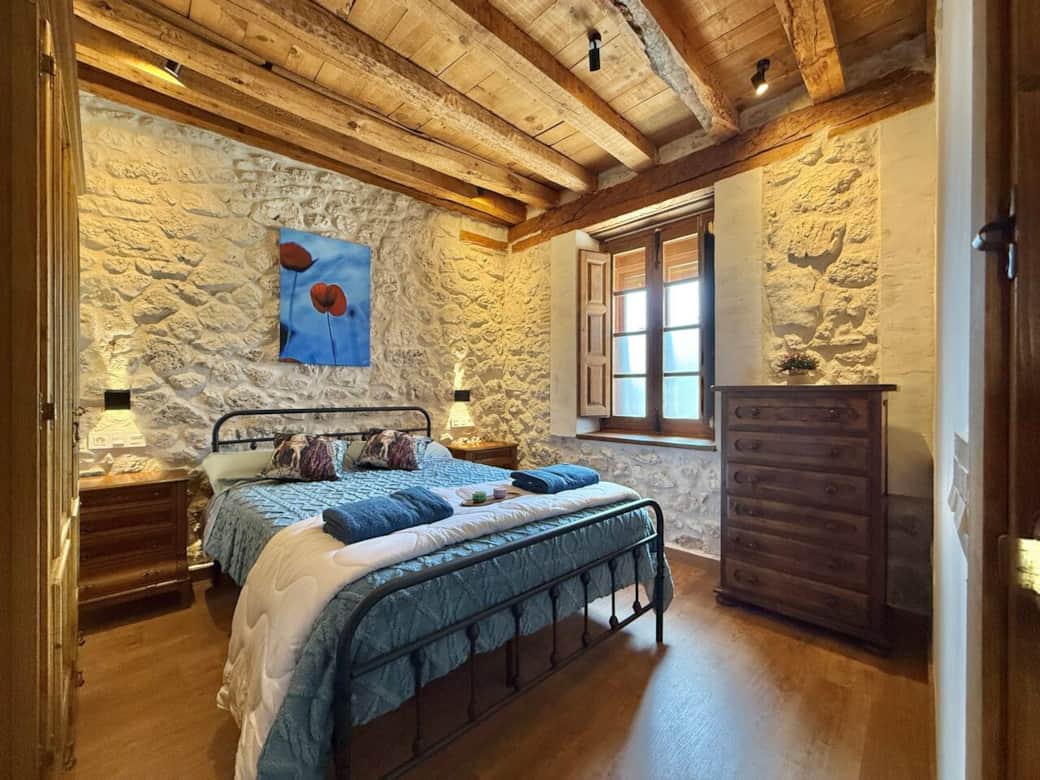 Dormitorio con cama de matrimonio, paredes de piedra y techo de madera que crean un ambiente cálido y auténtico. Perfecto para descansar y disfrutar de la tranquilidad rural. Dormitorio con cama de matrimonio, paredes de piedra y techo de madera que crean un ambiente cálido y auténtico. Perfecto para descansar y disfrutar de la tranquilidad rural.