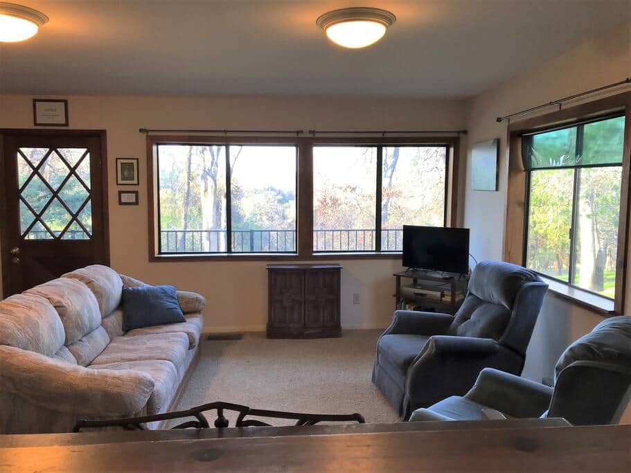 The living room looks out across the oak woodland, with a few distant rolling hills.