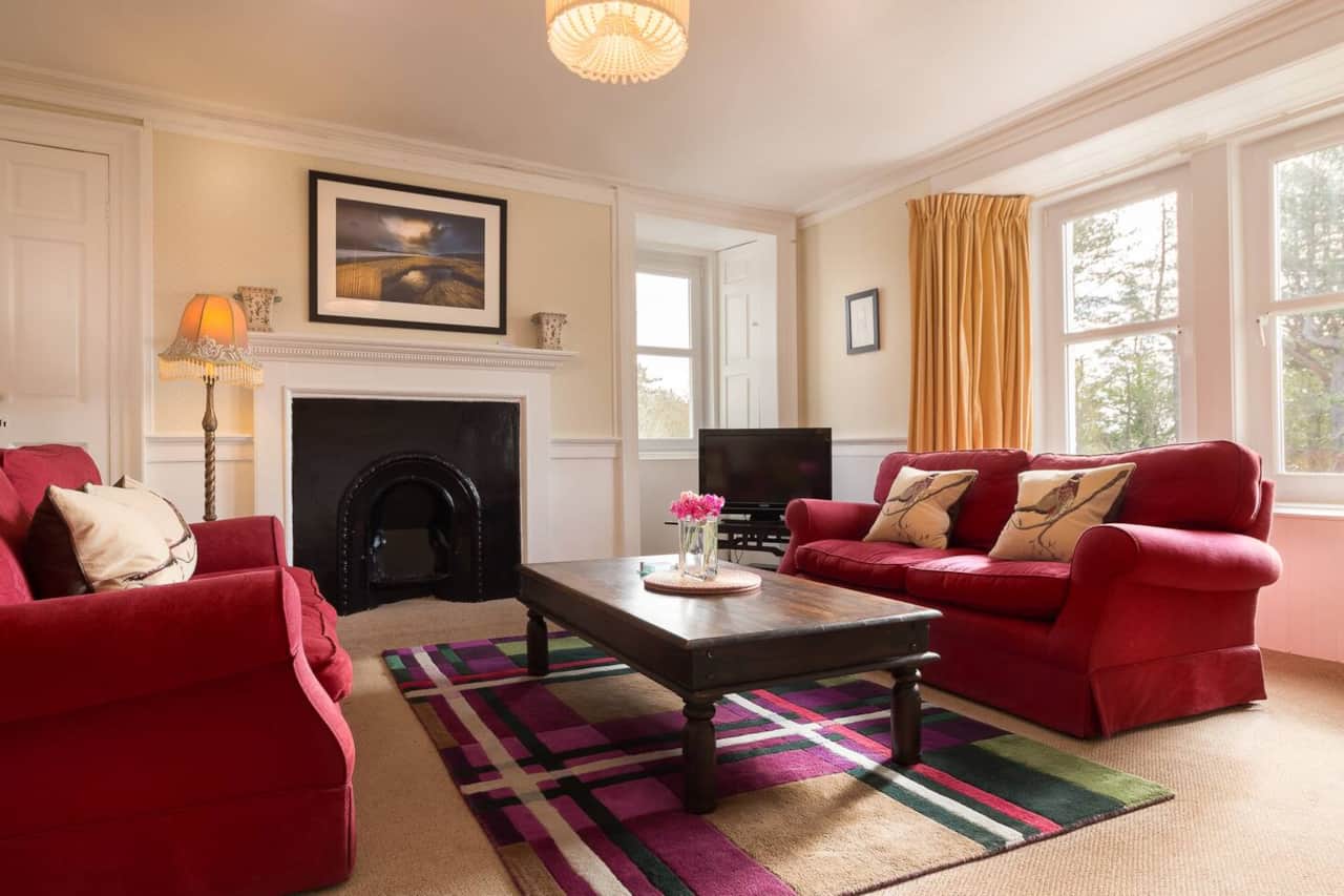 Living room with original fireplace and red sofas