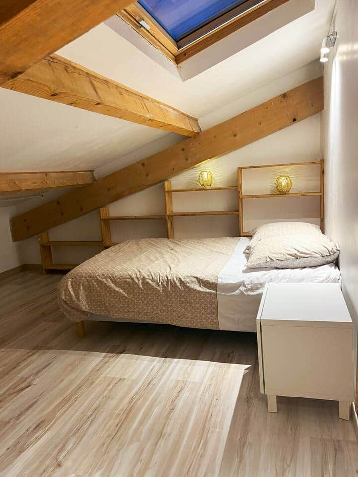 Une grande pièce en sous-pente à l'étage avec un lit 140 et des rangements.