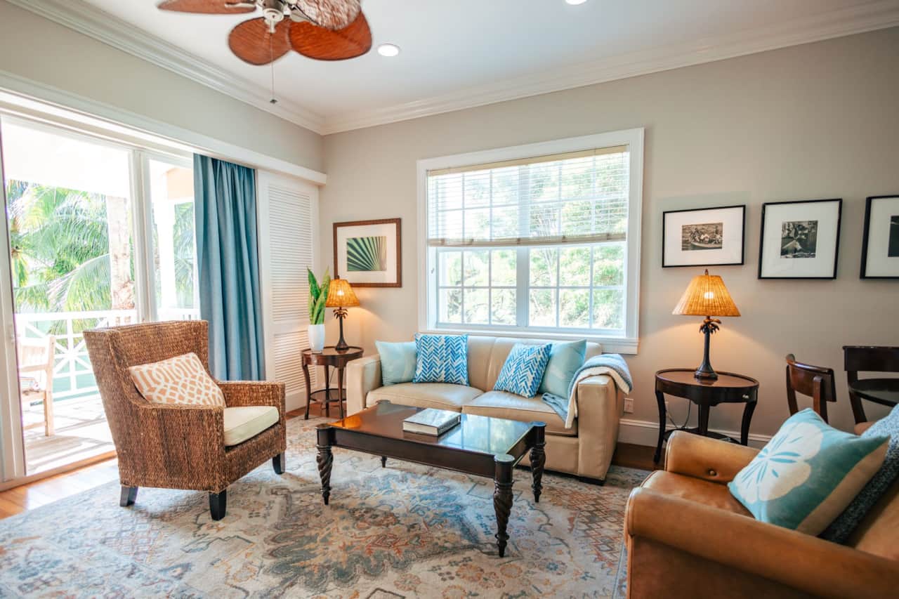 Living room seating with ceiling fan and glass doors opening to the balcony seating