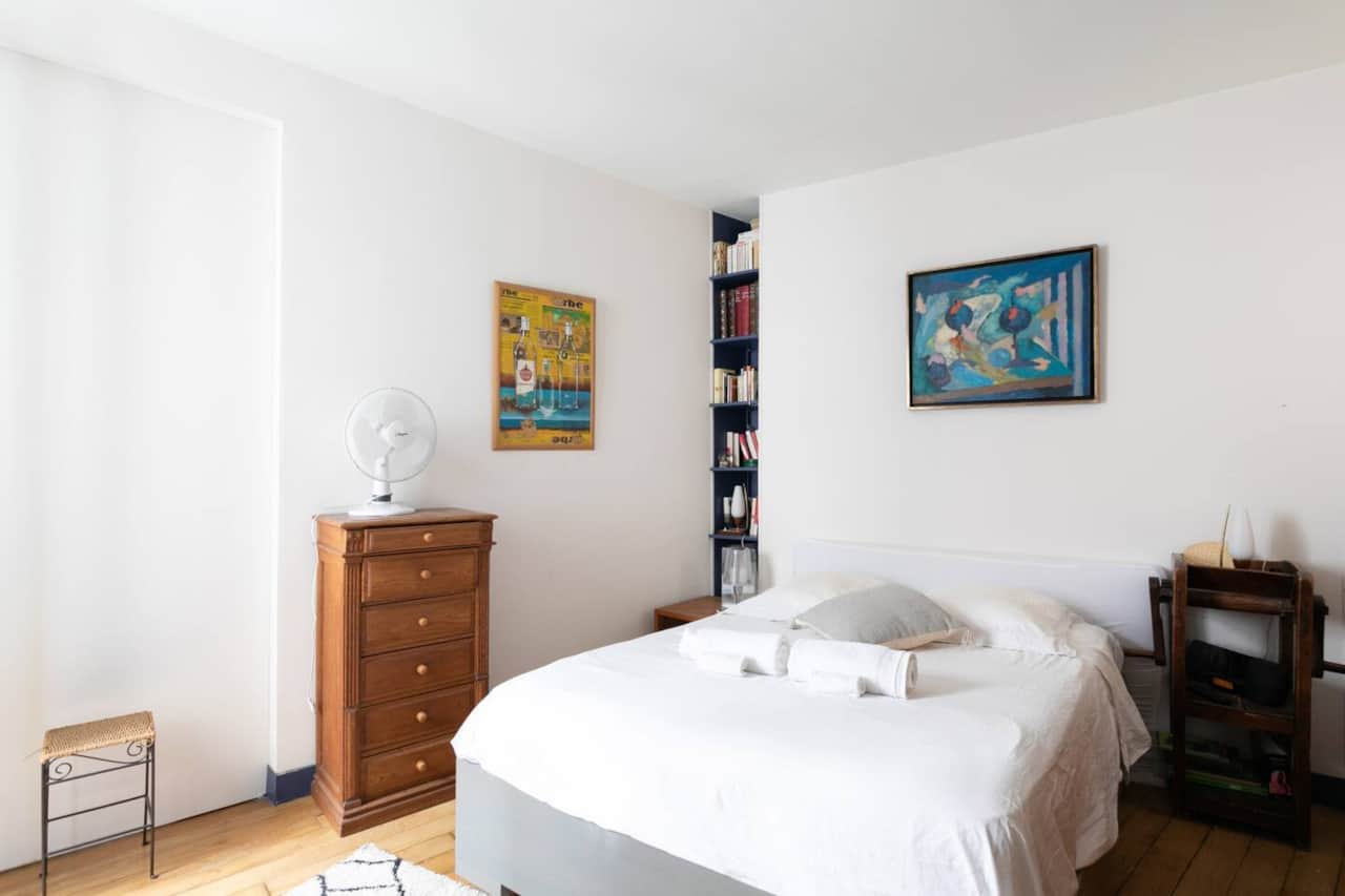La chambre est un havre de paix, dotée d'un lit double confortable avec du linge de lit blanc impeccable. La pièce est accentuée par des œuvres d'art colorées, créant une atmosphère vibrante mais relaxante.
