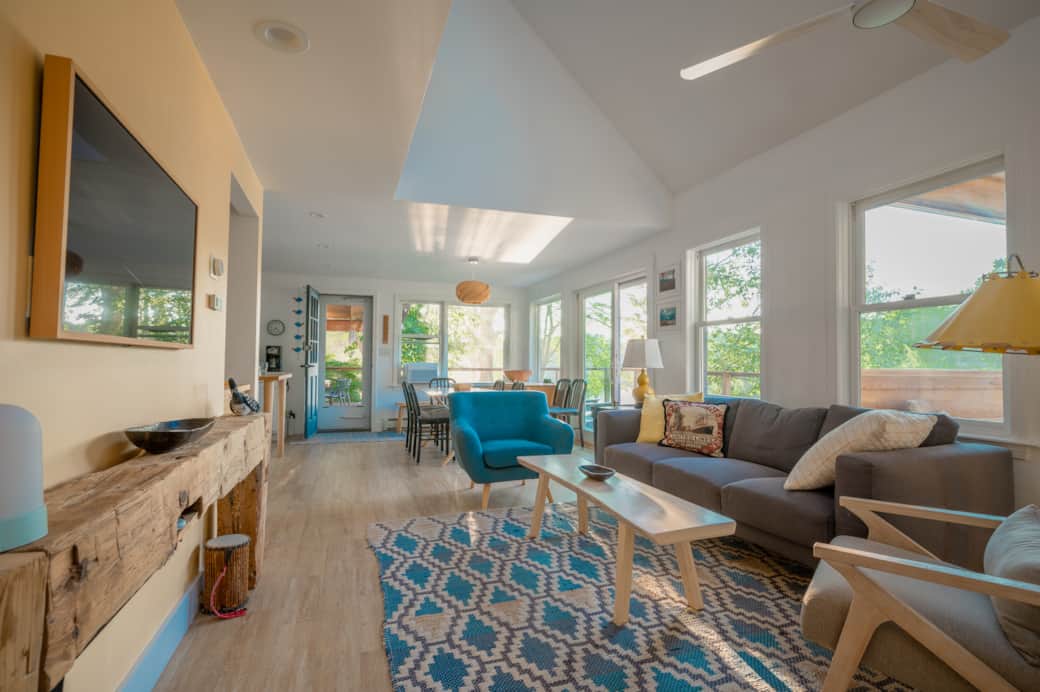 The open living/dining area is shaded by trees.