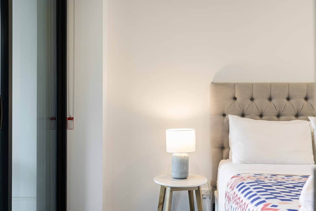 This serene bedroom is designed for a peaceful sleep. The plush bed with a tufted headboard and crisp white linens ensures comfort. The soft lighting from the bedside lamp adds a cozy ambiance. Perfect for travelers seeking a tranquil retreat .