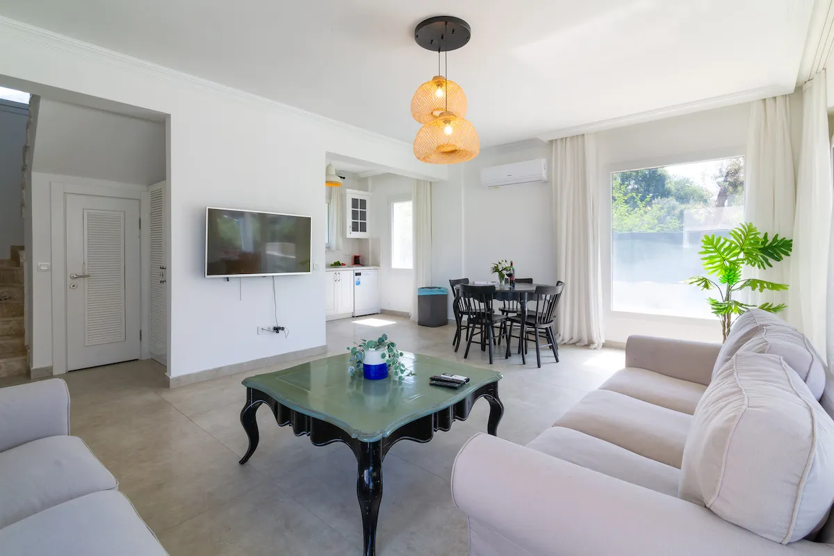 Living room with a sofa, coffee table, television, and dining area in Villa Nergis 1, Göcek.