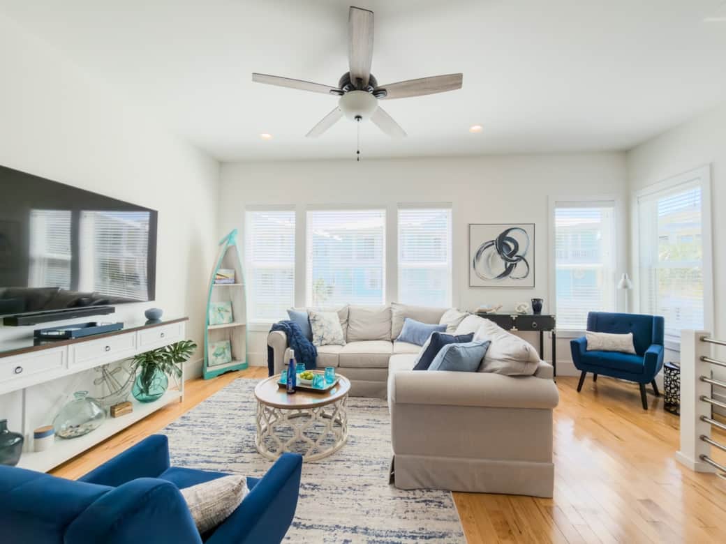 Bright, coastal living room with comfortable seating, large 75 inch Smart TV with Dolby soundbar and plenty of space for the whole group to relax after a beach day.