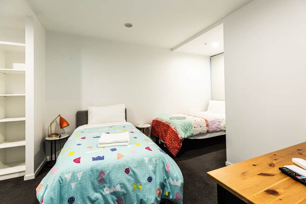 The room features two cozy beds with colorful bedding, perfect for families or friends traveling together. The playful decor adds a touch of whimsy, while the desk provides a practical workspace, a cheerful retreat that ensures a good night's sleep.