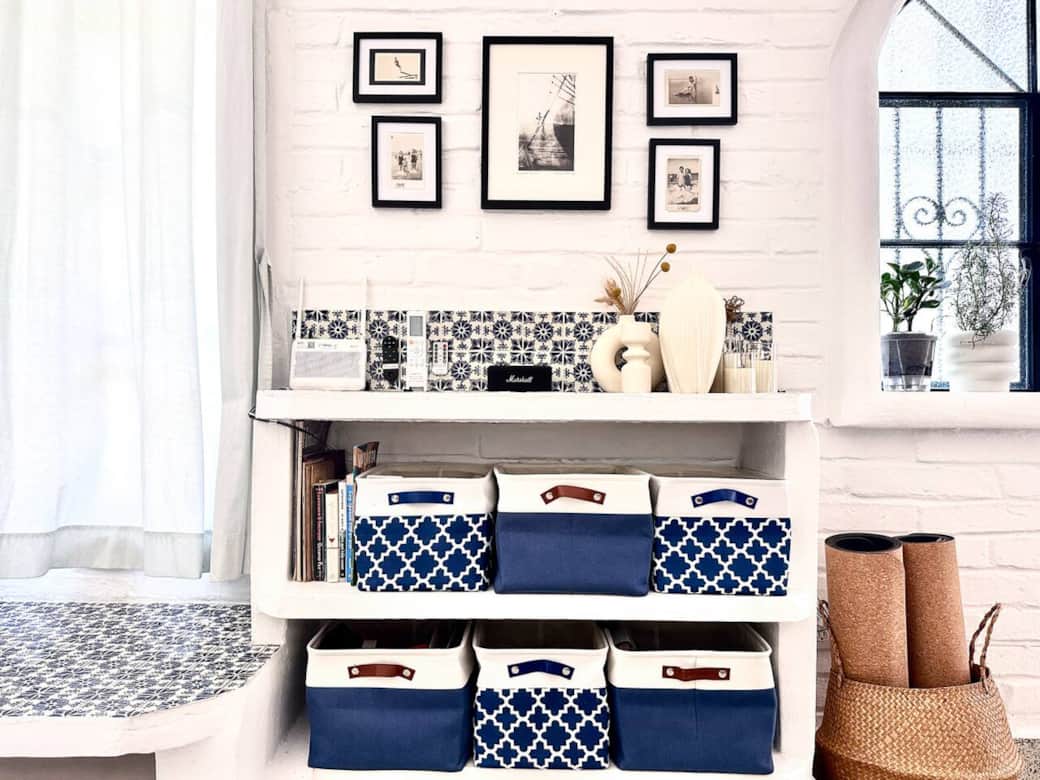 Stylish shelf with curated art, books, a Bluetooth Marshall speaker, remote control center, and cork yoga mats — blending function and design for a calm, organized space.