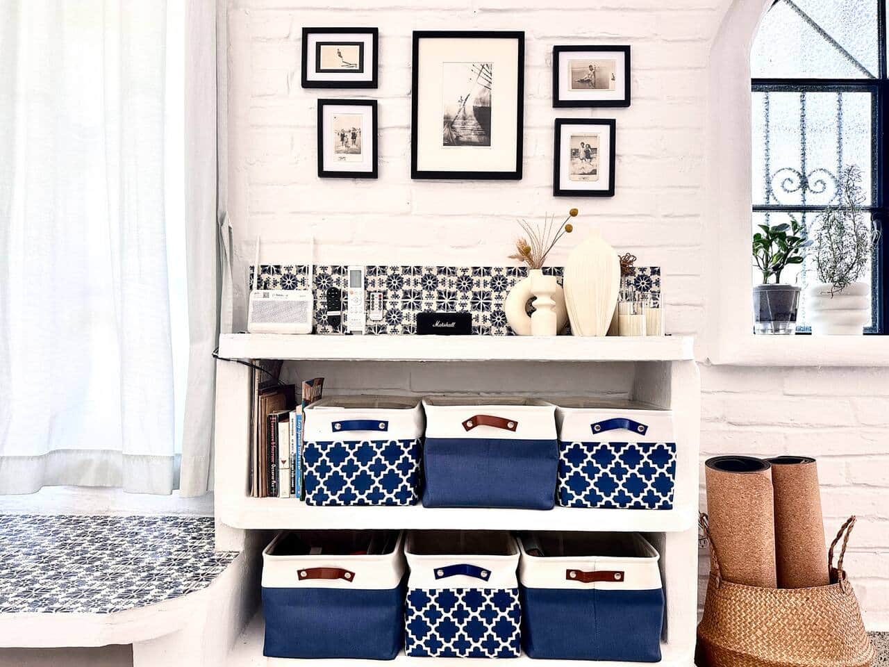 Stylish shelf with curated art, books, a Bluetooth Marshall speaker, remote control center, and cork yoga mats — blending function and design for a calm, organized space.