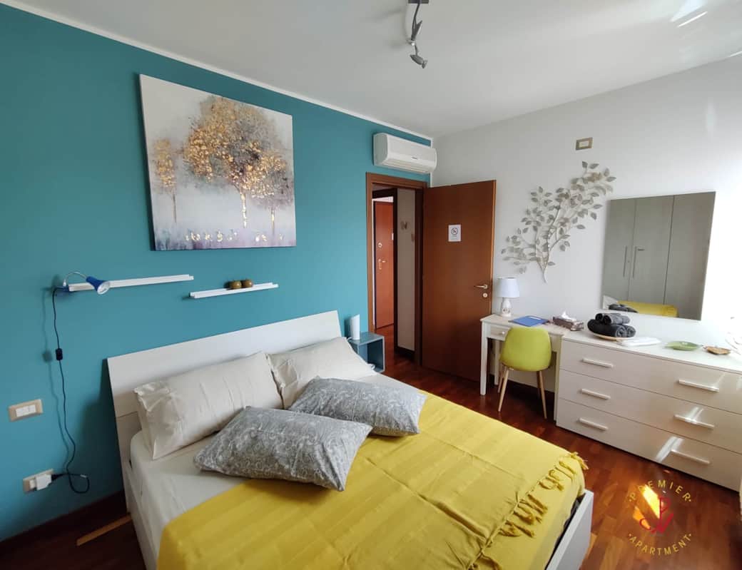 Dormitorio luminoso con escritorio, cómoda, espejo y suelo de parquet.