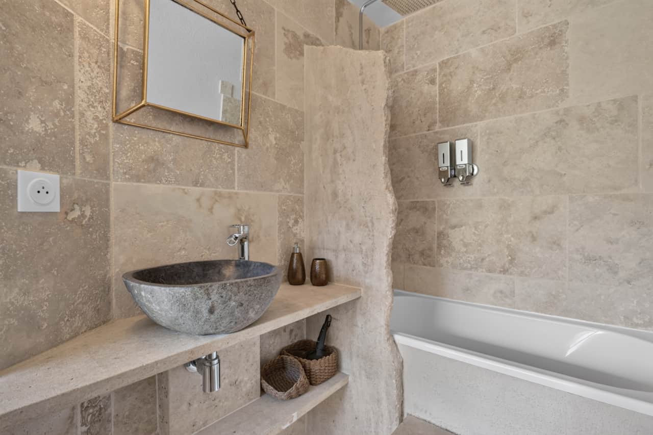 Salle de bain en travertin, baignoire et vasque en pierre pour un vrai moment détente.