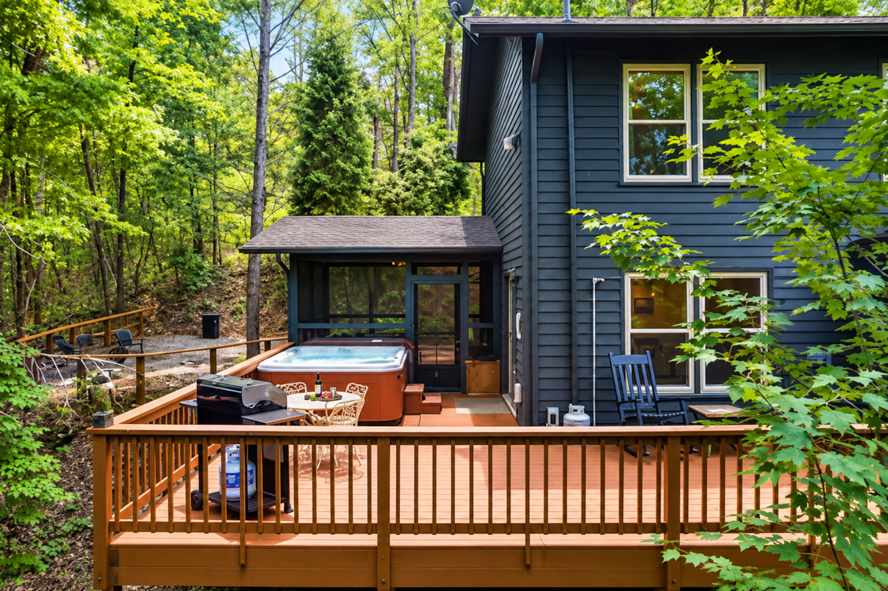 Spacious rear deck with hot tub, outdoor seating, and a quiet wooded setting