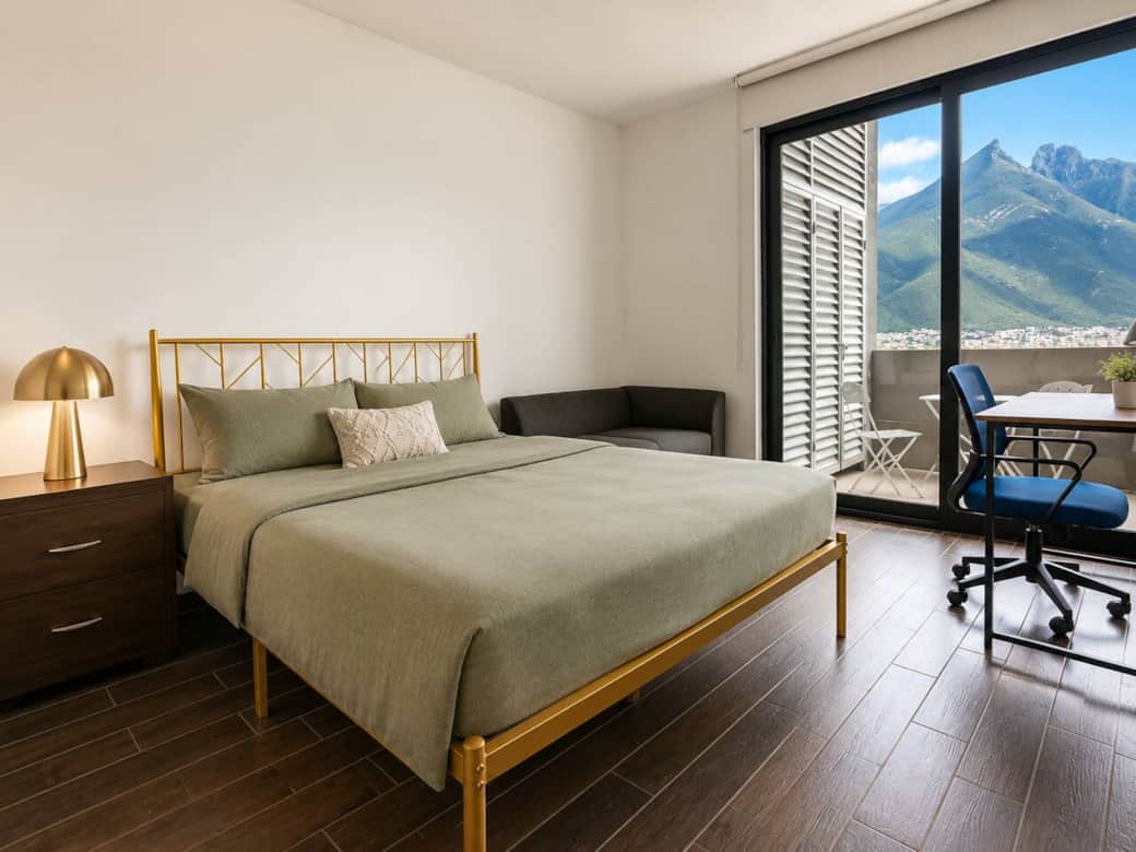 Bright bedroom with a gold-frame bed, and a dedicated workspace by the balcony. Large windows bring in natural light and stunning mountain views of Cerro de la Silla, creating a calm and comfortable retreat in Monterrey. Bright bedroom with a gold-frame bed, and a dedicated workspace by the balcony. Large windows bring in natural light and stunning mountain views of Cerro de la Silla, creating a calm and comfortable retreat in Monterrey.