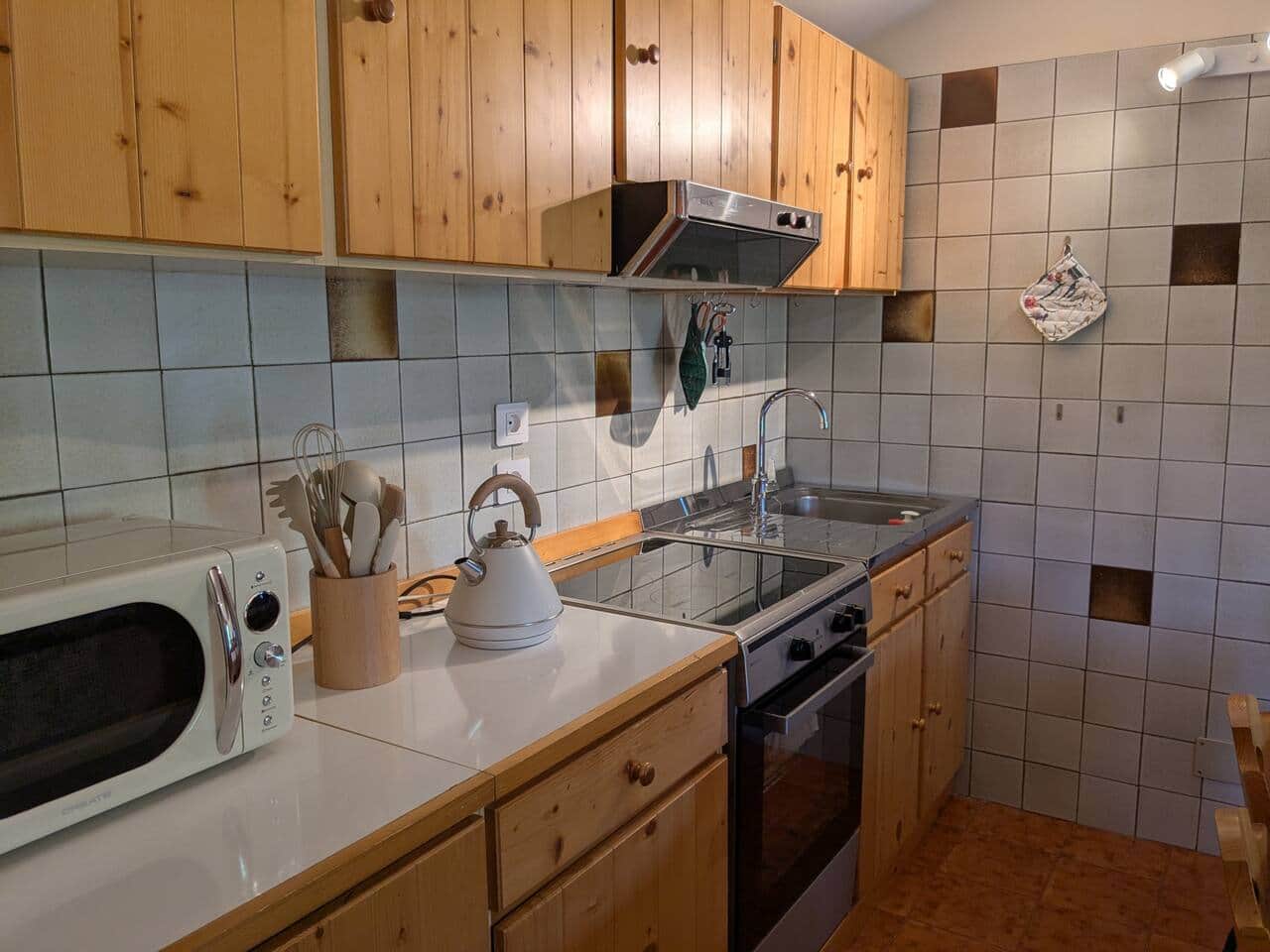 Zona cottura con piano a induzione, forno, bollitore e lavello in acciaio inox