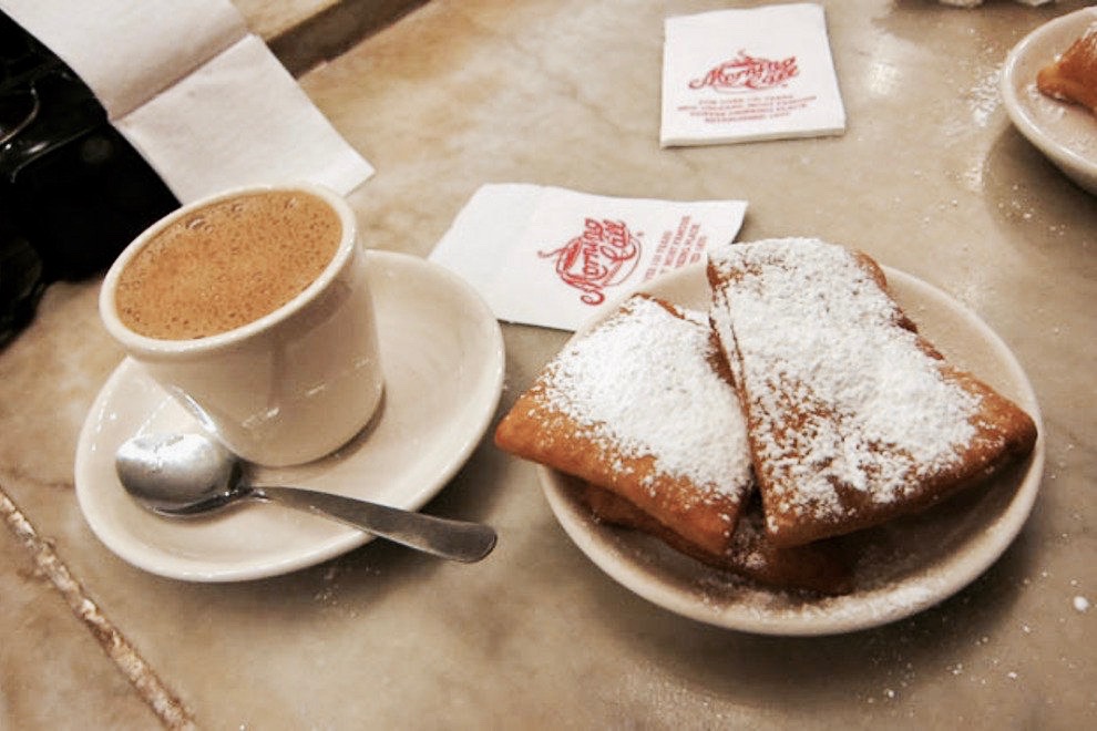 A cup of coffee and a plate of beignets on a table