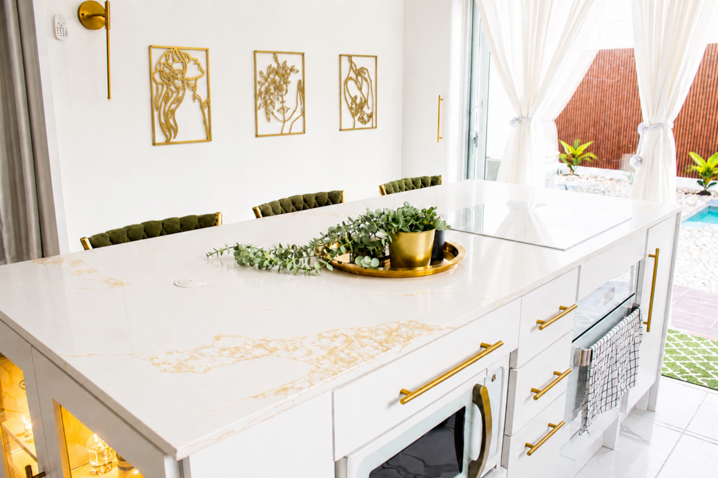 Bright modern kitchen with marble island, gold accents & pool views. Bright modern kitchen with marble island, gold accents & pool views.