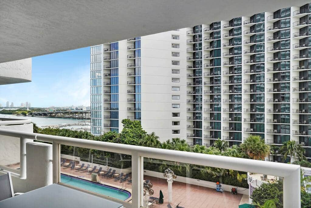 Fully furnished balcony with views of Biscayne Bay, pool, and downtown Miami skyline